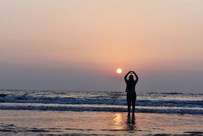 Man standing on beach against sky during sunset