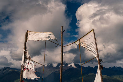 Low angle view of torn banner against cloudy sky