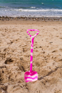 Close-up of pink umbrella on beach against sky