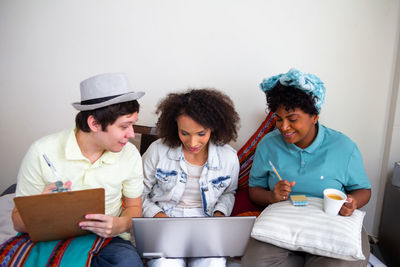 Smiling friends using laptop while sitting at table