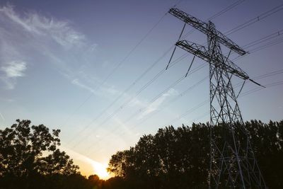 Low angle view of silhouette electricity pylon against sky during sunset