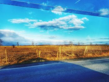 Road by trees against blue sky