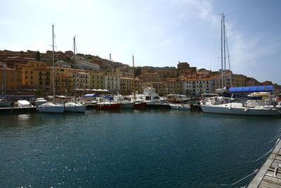 Sailboats moored at harbor against sky