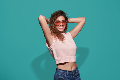 Portrait of smiling young woman standing against blue sky