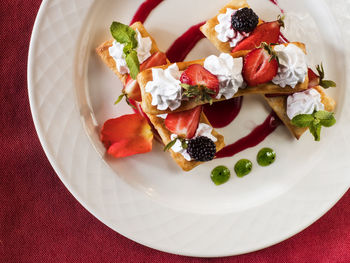 High angle view of puff pastries with strawberries served in plate on table