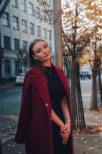 Young woman standing against wall in city