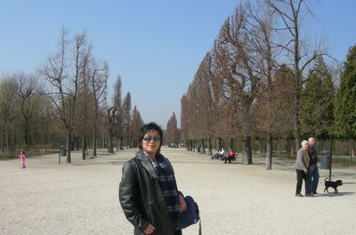 Portrait of young man sitting on bare trees against clear sky