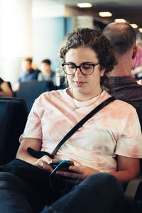 Young woman using mobile phone while sitting on seat