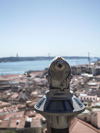 Close-up of hand-held telescope against town