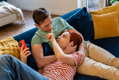 Side view of mother and daughter sitting on sofa at home