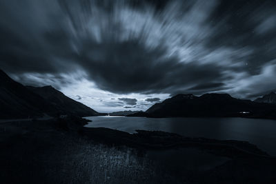 Scenic view of lake and mountains against cloudy sky