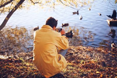 Rear view of man photographing at lakeshore