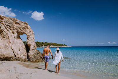 Rear view of women on beach against sky
