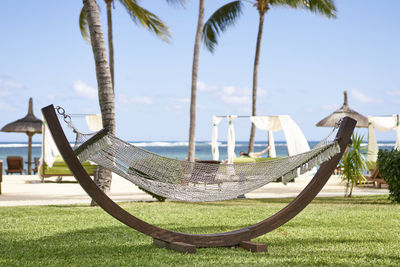 Empty chairs by swimming pool against sky