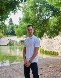 Portrait of young man standing against trees