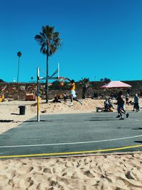 People on beach against clear blue sky