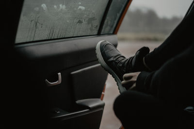 Low section of man wearing shoe sitting in car