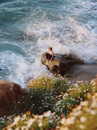 High angle view of boy sitting on rock at beach