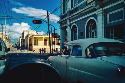 Cars on street in city against sky