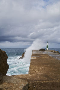 Green lighthouse struck by ocean waves, colors of nature