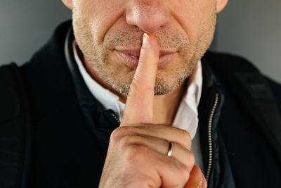Midsection of man with finger on lips