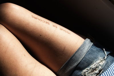 Shadow of text on woman thigh while sitting in car
