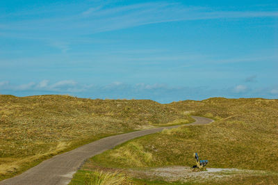 Road amidst field against sky