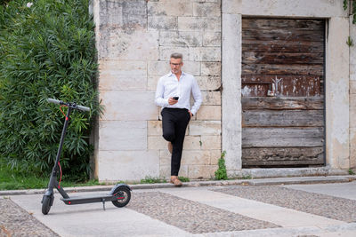 Young businessman using phone near electric scooter. focus on scooter