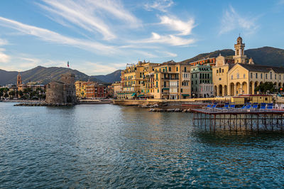 Buildings by river against sky