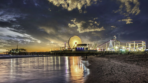 View of ferris wheel in city against cloudy sky