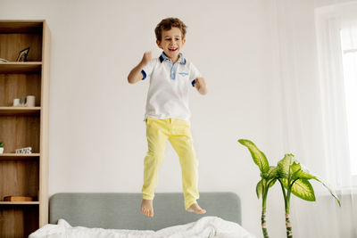 Playful boy jumping on bed