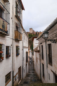 Footpath amidst buildings in town against sky