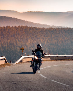 Rear view of man riding motorcycle on road