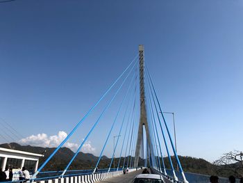 Low angle view of suspension bridge against clear blue sky