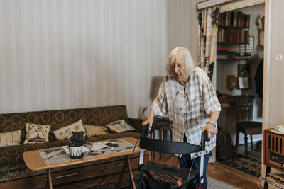 Senior woman using mobility walker while walking at home