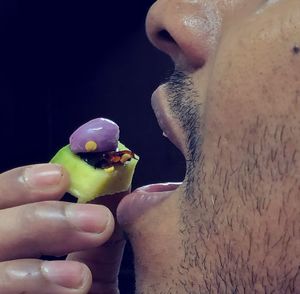 Close-up of hand holding ice cream against black background