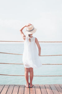 Rear view of woman standing on pier against sea