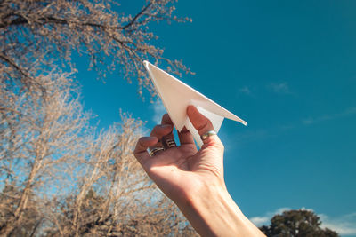 Person holding umbrella against blue sky