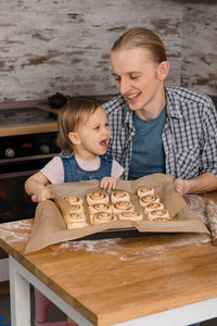 Father and child cooking on the kitchen with fun. family baking cinnabon