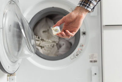 Midsection of person washing clothes in washing machine