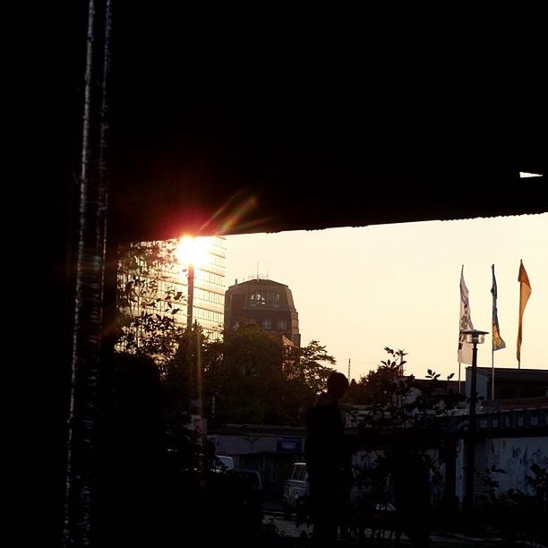 architecture, built structure, building exterior, silhouette, sunset, sun, clear sky, city, low angle view, sunlight, sky, transportation, building, outdoors, copy space, sunbeam, no people, lens flare, crane - construction machinery, dusk