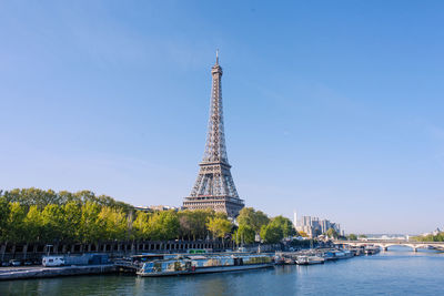 Eiffel tower by seine river against blue sky