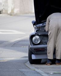 Low section of man on car on road