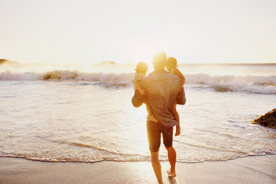Rear view of man and woman walking on beach