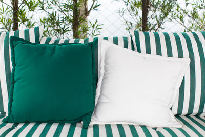 Cushions on striped sofa against plants