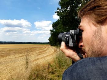 Man photographing on field against sky