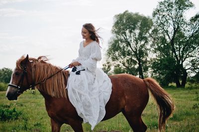 Young woman riding horse on field