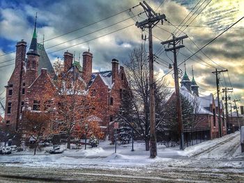 Snow covered houses against cloudy sky