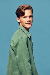 Portrait of young man standing against clear blue background