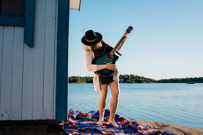 Full length of woman standing by water against clear sky